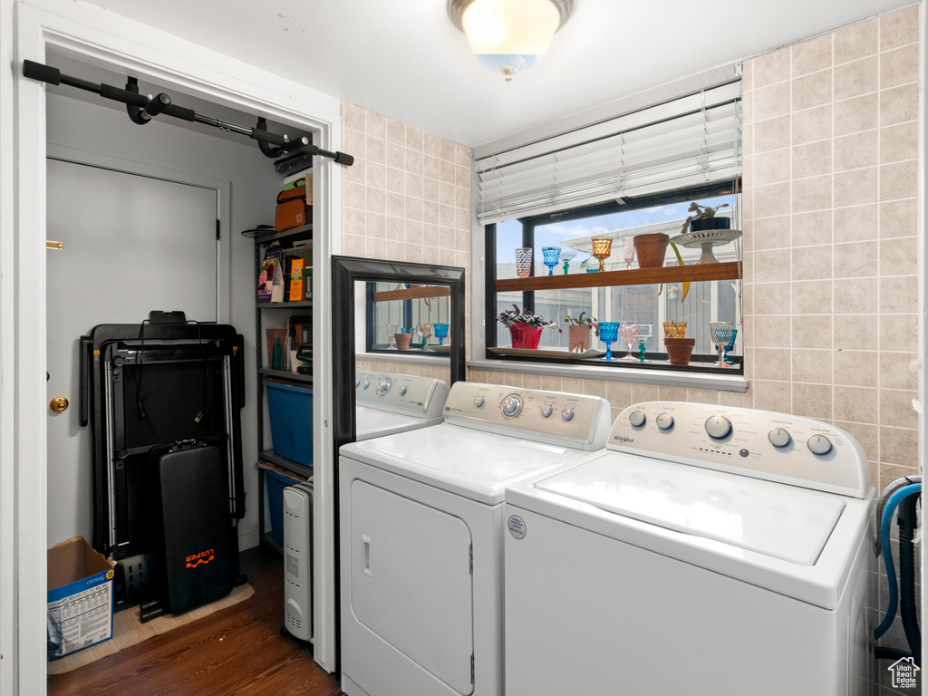 Laundry room with washer and dryer, laundry area, tile walls, and wood finished floors