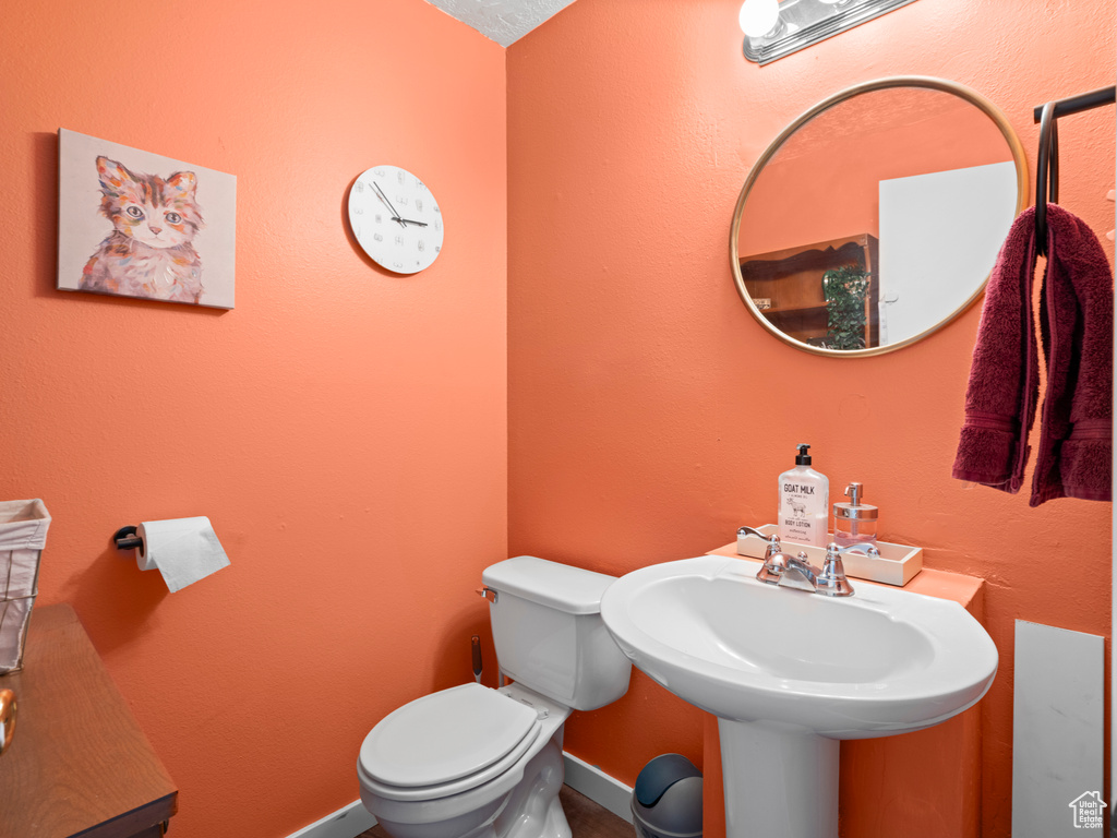 Half bath with a sink, toilet, and baseboards