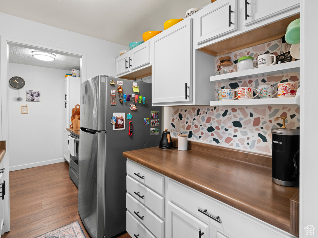 Kitchen featuring open shelves, stainless steel appliances, white cabinetry, a textured ceiling, and wood finished floors