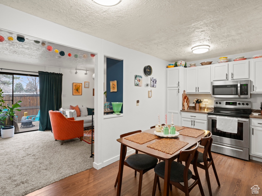 Kitchen featuring white cabinetry, a textured ceiling, appliances with stainless steel finishes, and wood finished floors