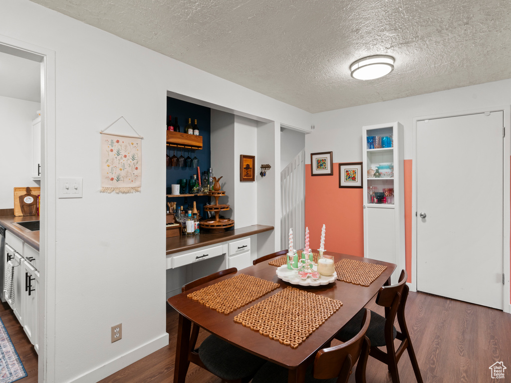 Dining room featuring a textured ceiling and dark wood-style flooring