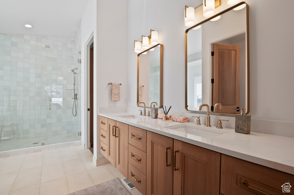 Full bathroom featuring double vanity, tile patterned flooring, a sink, and a shower stall