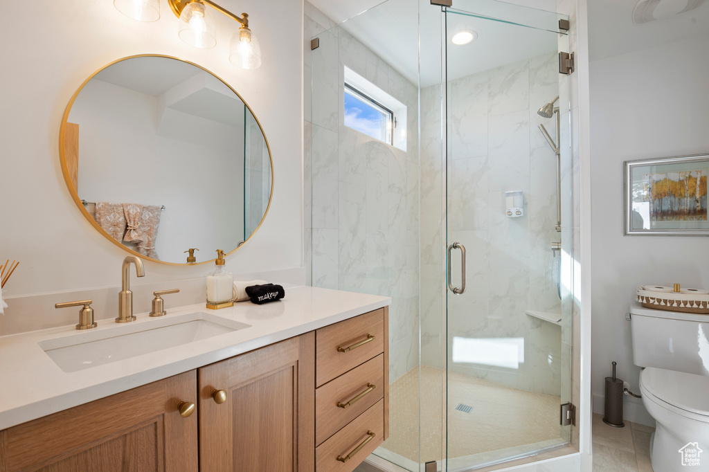 Full bathroom featuring a marble finish shower, vanity, and toilet