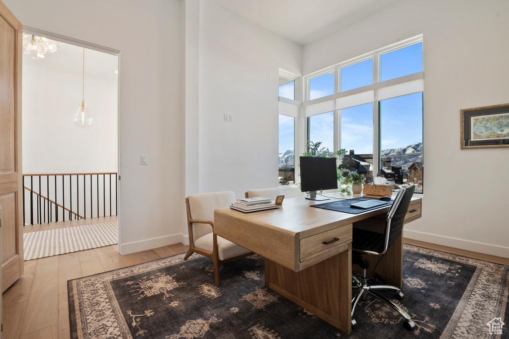 Home office featuring a notable chandelier, a high ceiling, baseboards, and hardwood / wood-style floors