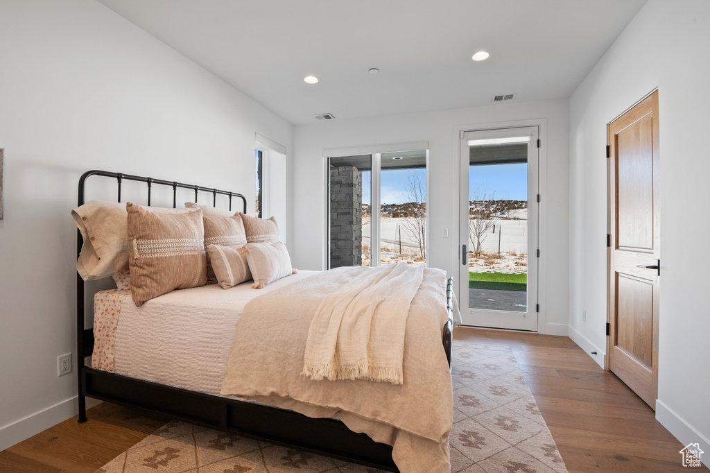 Bedroom with baseboards, visible vents, wood finished floors, access to outside, and recessed lighting