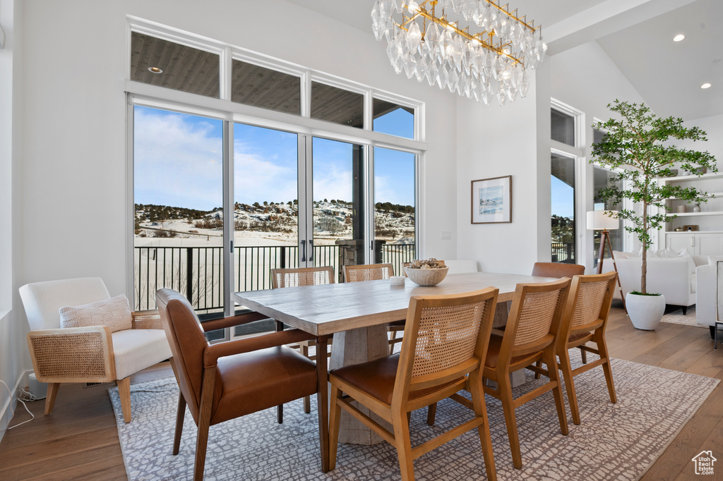 Dining space with hardwood / wood-style flooring, a high ceiling, an inviting chandelier, and recessed lighting