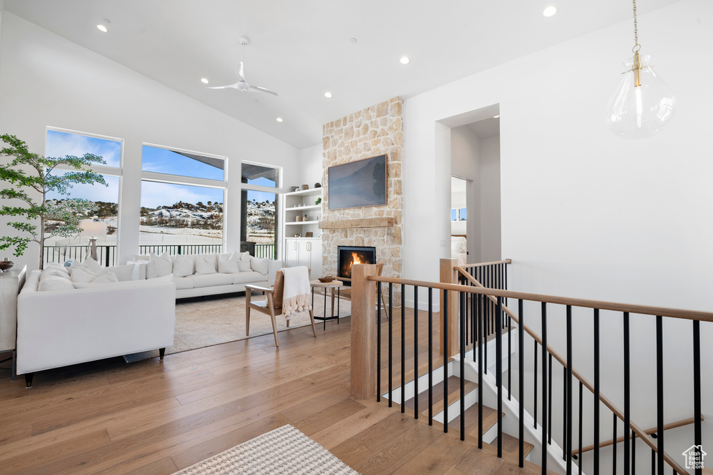 Living room featuring recessed lighting, ceiling fan, a stone fireplace, wood finished floors, and high vaulted ceiling