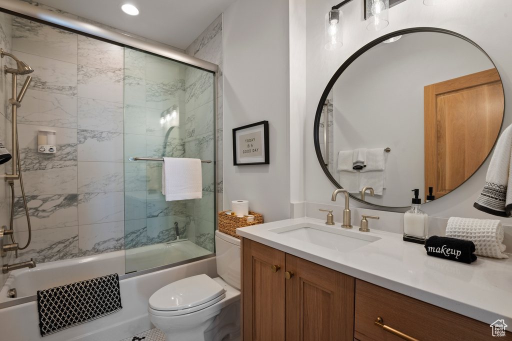 Bathroom featuring combined bath / shower with glass door, vanity, and toilet