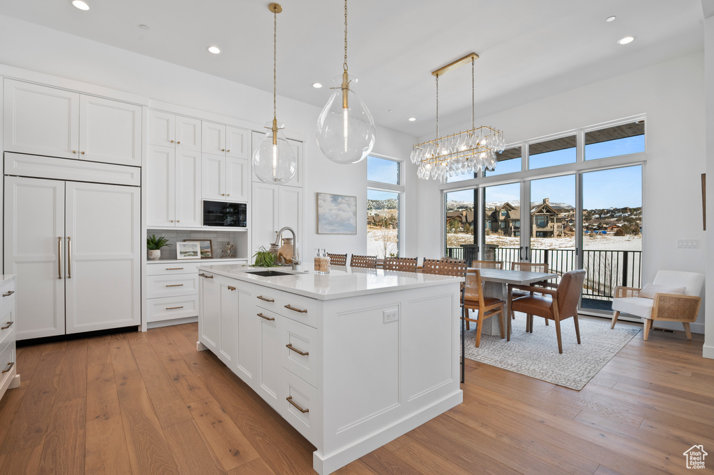 Kitchen featuring light wood-style floors, plenty of natural light, paneled refrigerator, and a sink