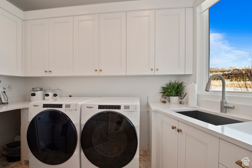 Laundry area featuring cabinet space, a sink, and washing machine and clothes dryer