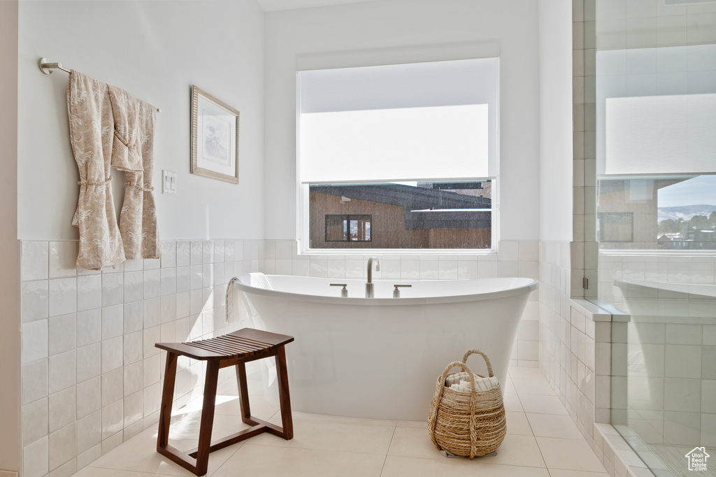 Bathroom featuring a freestanding tub, a wainscoted wall, tile walls, and tile patterned floors