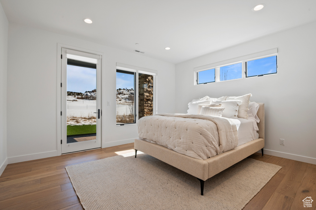 Bedroom with access to exterior, recessed lighting, visible vents, and wood finished floors