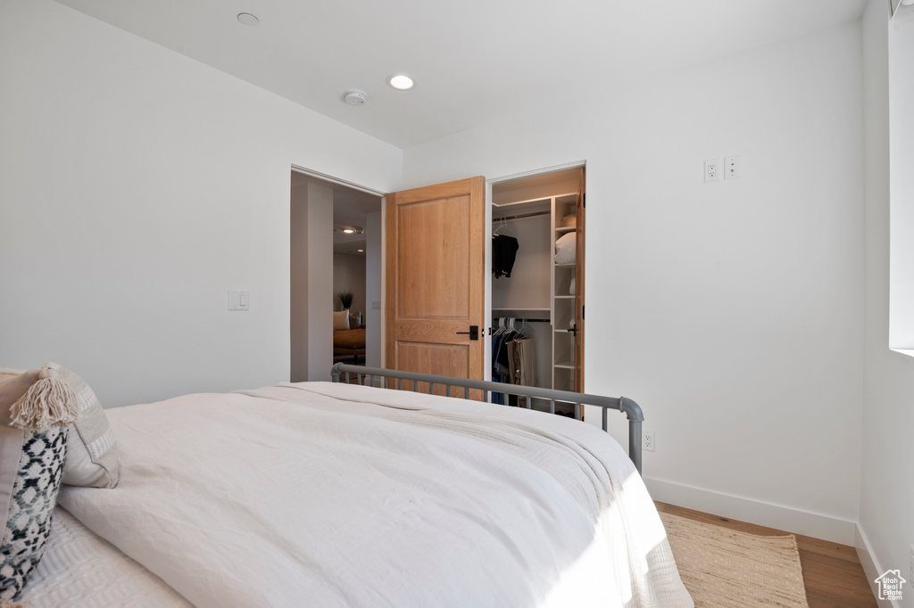 Bedroom featuring recessed lighting, a closet, a spacious closet, wood finished floors, and baseboards