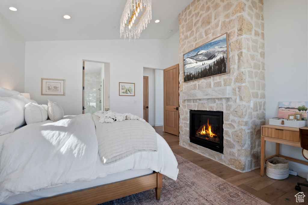 Bedroom featuring lofted ceiling, a stone fireplace, wood finished floors, and recessed lighting