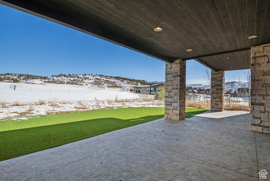 Snow covered patio with a yard and a fenced backyard