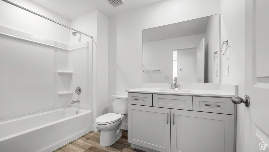 Bathroom featuring shower / tub combination, toilet, wood finished floors, vanity, and visible vents