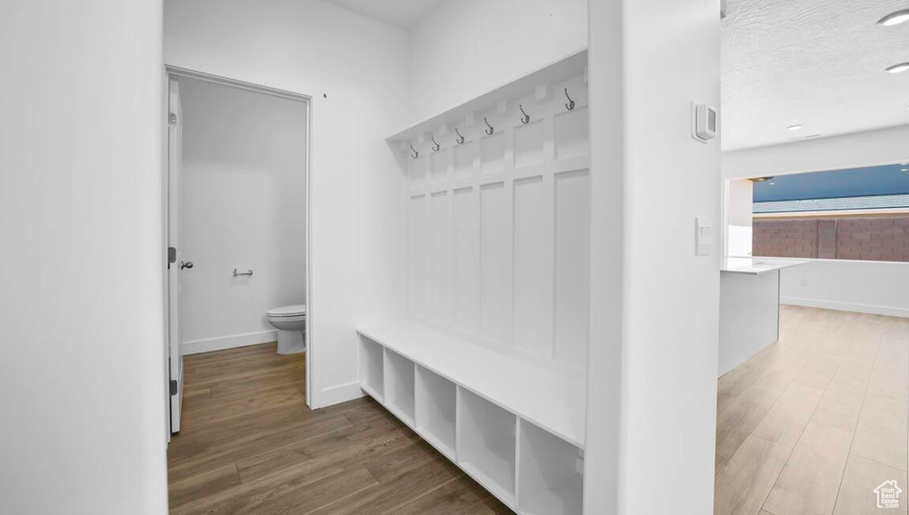Mudroom with a textured ceiling, baseboards, and wood finished floors