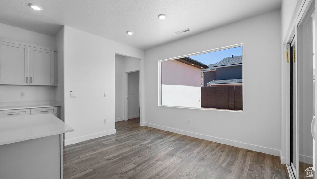 Unfurnished dining area featuring a textured ceiling, recessed lighting, wood finished floors, visible vents, and baseboards