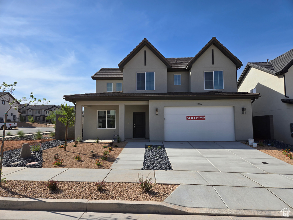 Traditional-style home with stucco siding, driveway, a porch, and an attached garage