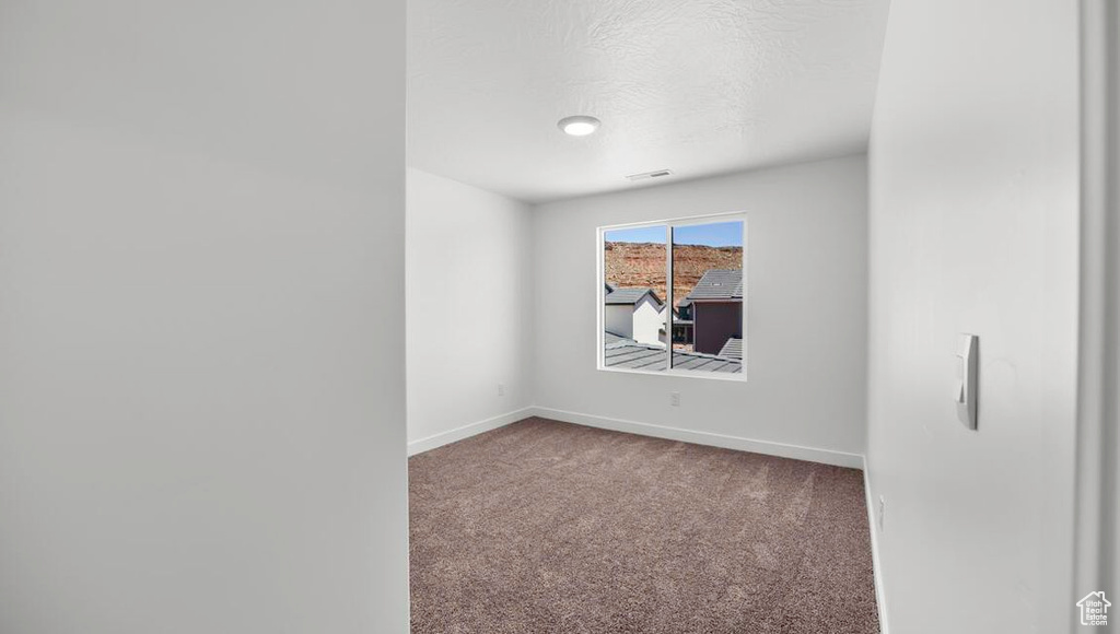 Carpeted empty room with visible vents, baseboards, and a textured ceiling