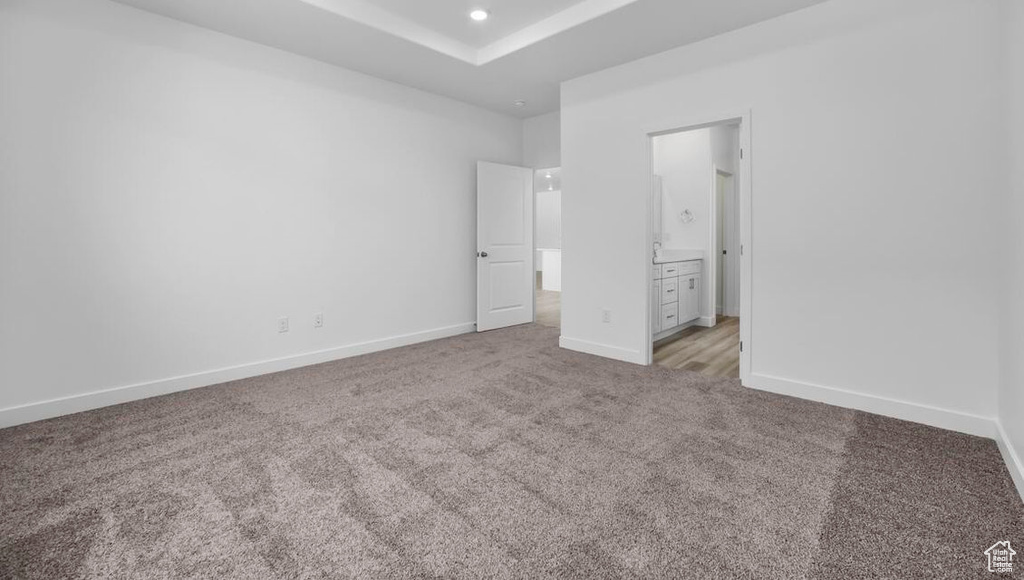 Unfurnished bedroom featuring light carpet, baseboards, ensuite bathroom, and recessed lighting