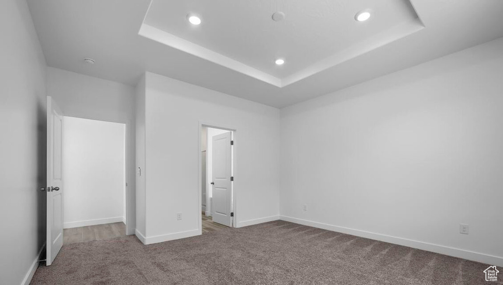 Unfurnished bedroom with carpet floors, recessed lighting, a raised ceiling, and baseboards