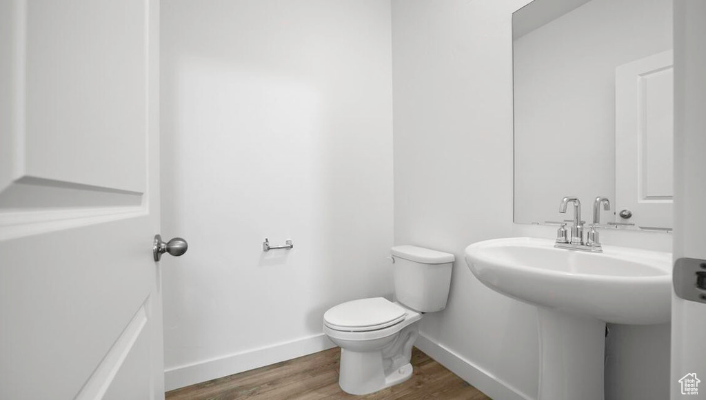 Half bath with wood finished floors, toilet, and baseboards