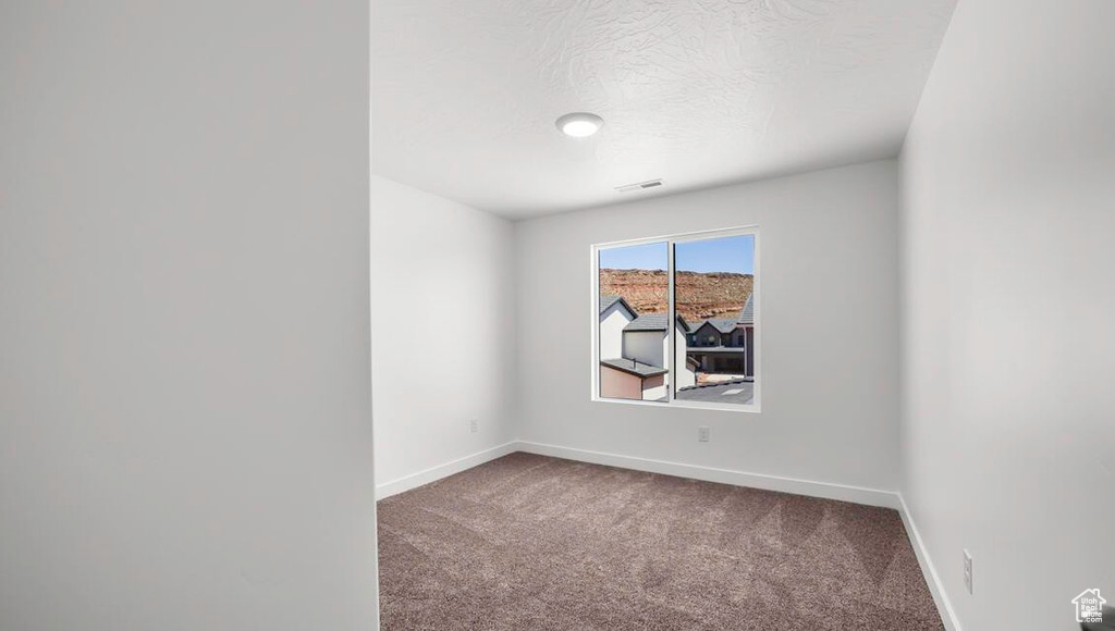 Carpeted empty room with visible vents, baseboards, and a textured ceiling