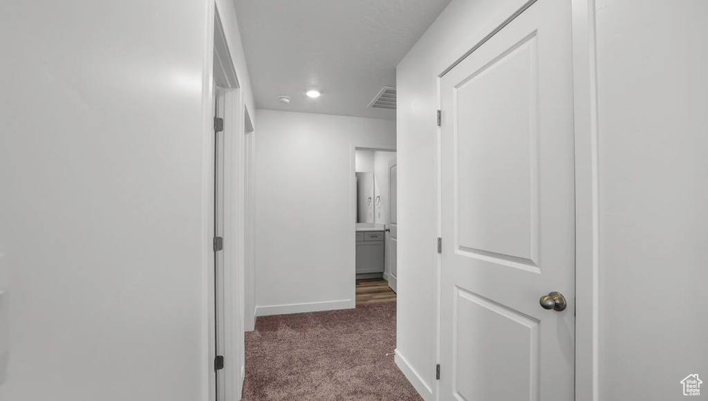 Corridor with carpet floors, visible vents, and baseboards