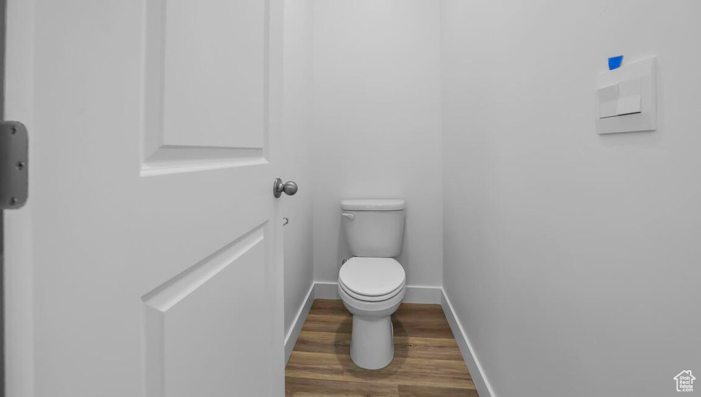 Bathroom featuring wood finished floors, toilet, and baseboards