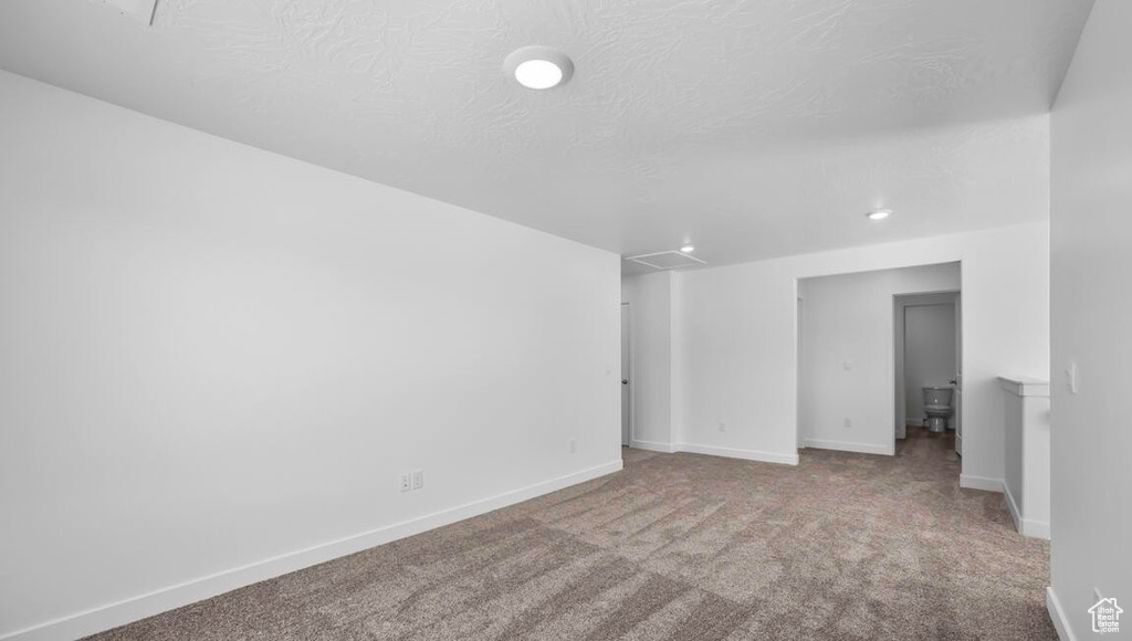 Empty room with carpet, a textured ceiling, and baseboards