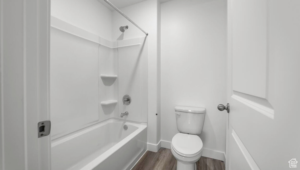 Bathroom with shower / bath combination, baseboards, toilet, and wood finished floors