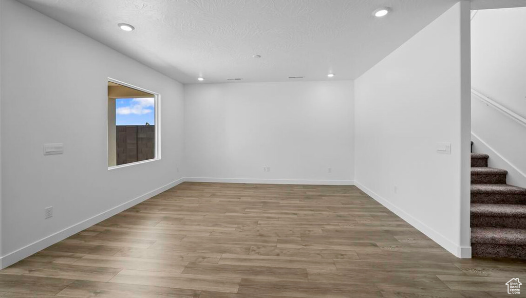 Spare room featuring recessed lighting, stairway, a textured ceiling, wood finished floors, and baseboards