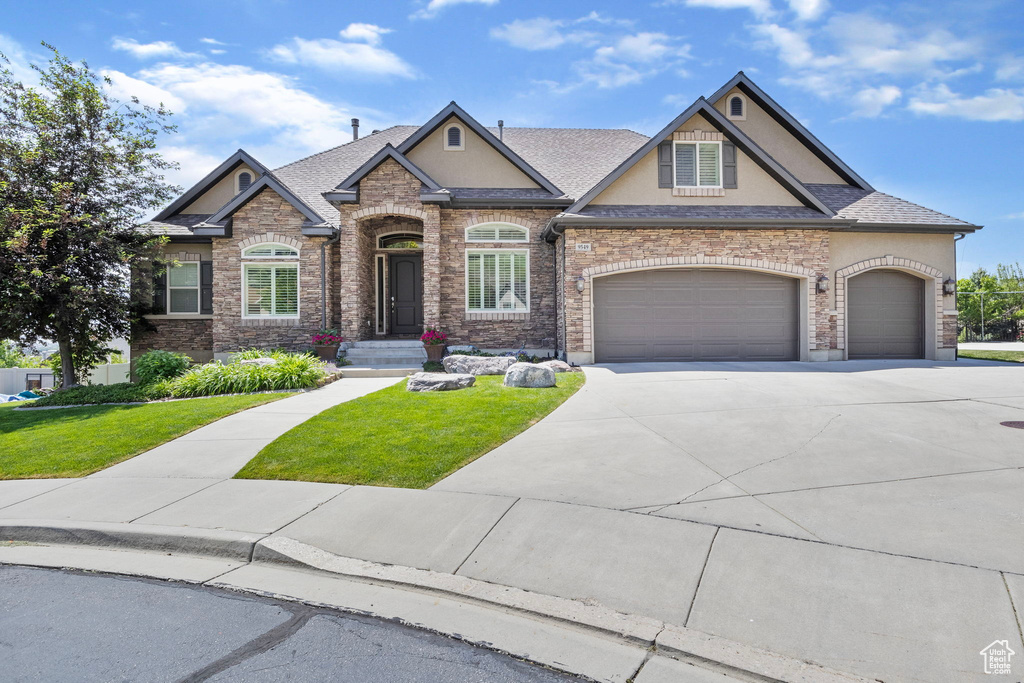 Craftsman-style home featuring driveway, a front yard, an attached garage, and stucco siding