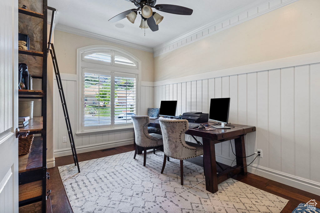 Office space featuring a wainscoted wall, visible vents, ornamental molding, and wood finished floors