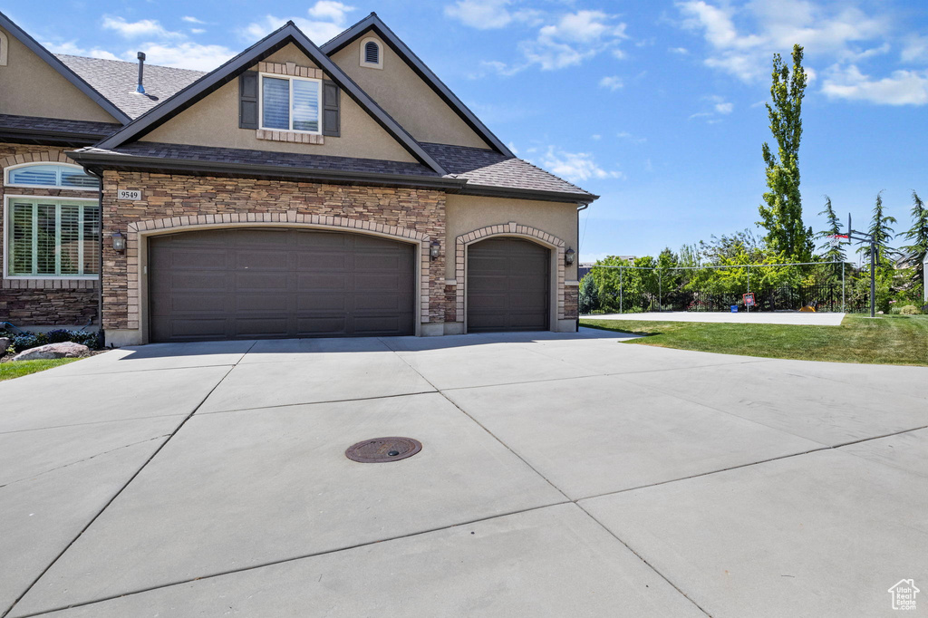 View of front of home with driveway, an attached garage, roof with shingles, and stucco siding