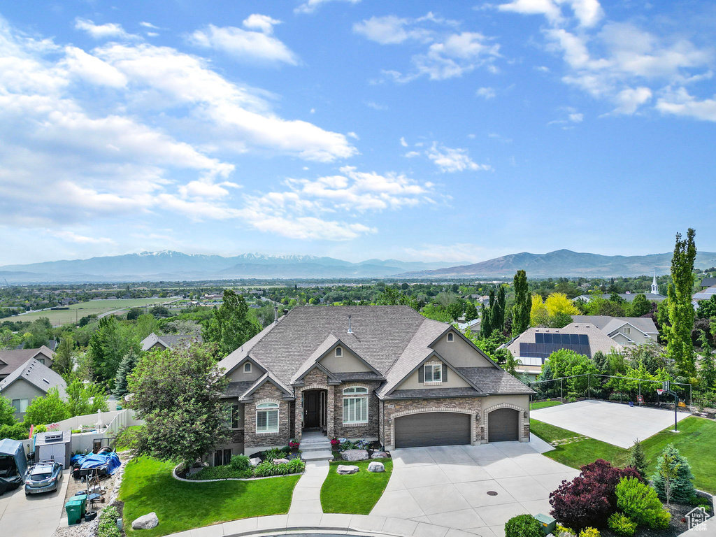 View of front of home with a shingled roof, a mountain view, fence, a garage, and a front lawn