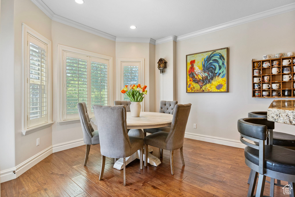 Dining room with recessed lighting, wood-type flooring, crown molding, and baseboards