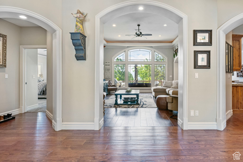 Interior space with a ceiling fan, baseboards, arched walkways, and hardwood / wood-style floors