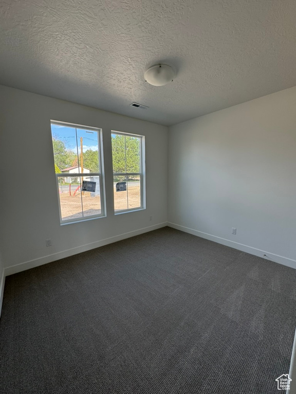 Empty room featuring a textured ceiling, visible vents, plenty of natural light, and baseboards