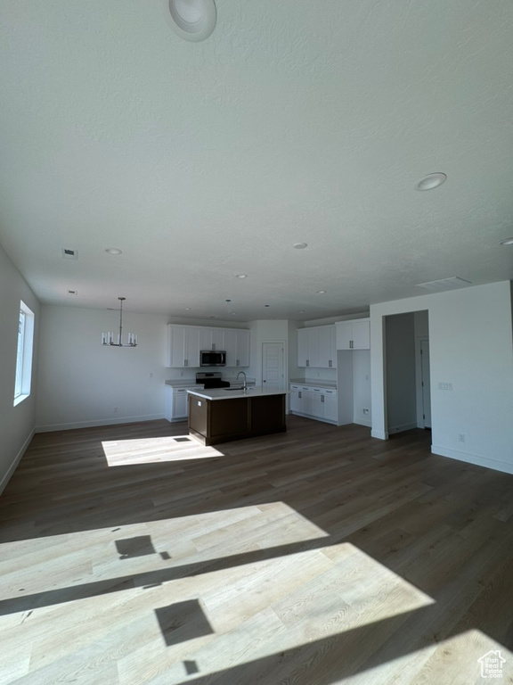 Unfurnished living room with baseboards, recessed lighting, dark wood-style flooring, and a sink