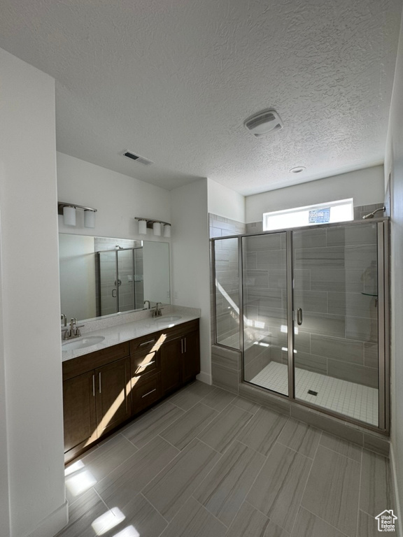 Full bath featuring double vanity, a sink, a shower stall, and visible vents