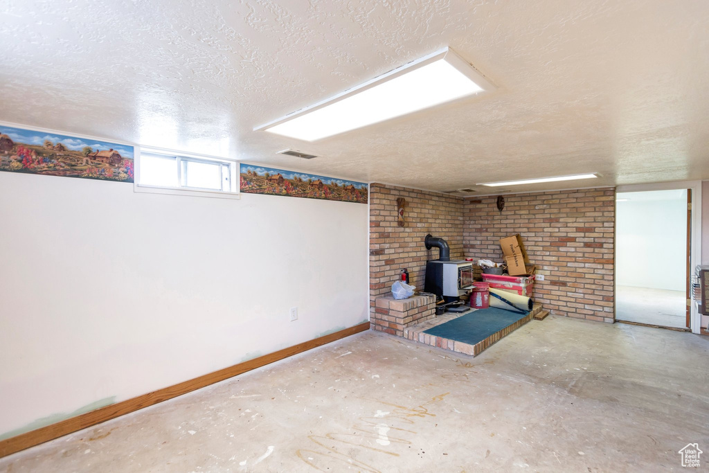 Below grade area with baseboards, a wood stove, a textured ceiling, and visible vents
