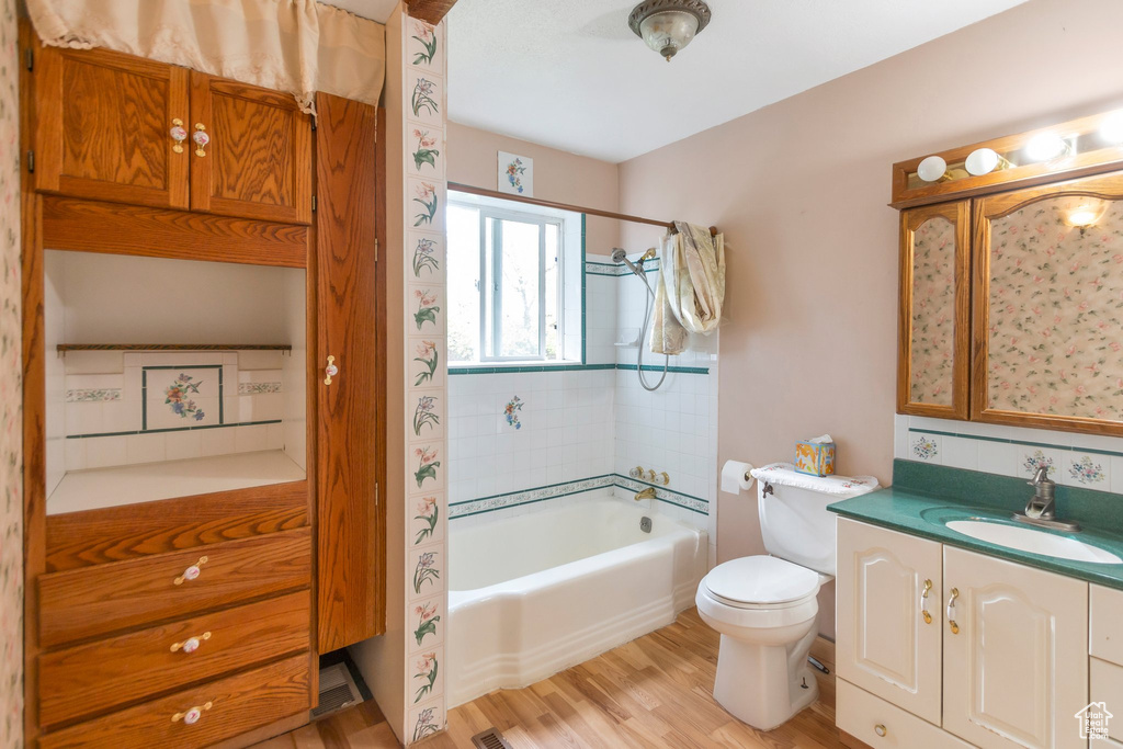 Full bathroom with vanity, wood finished floors, toilet, and shower / washtub combination