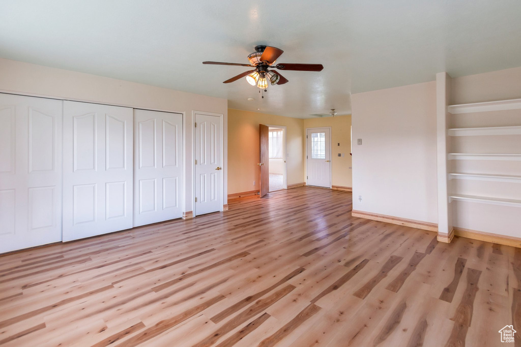 Unfurnished bedroom featuring multiple closets, baseboards, ceiling fan, and light wood-style flooring