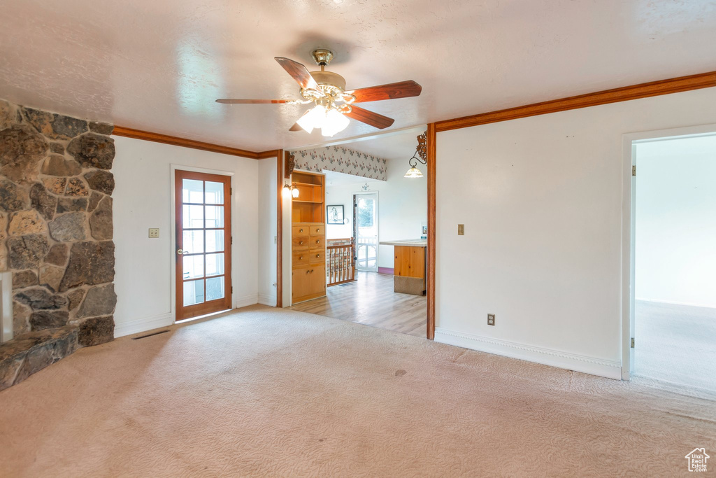 Unfurnished room featuring crown molding, baseboards, ceiling fan, and light colored carpet