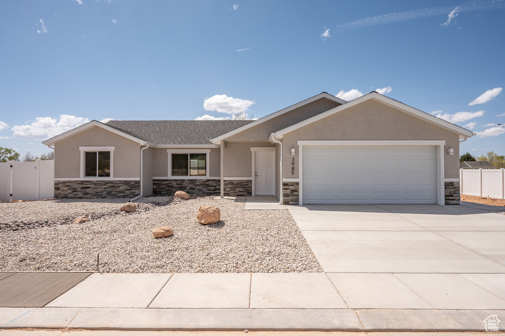 Ranch-style home with stucco siding, stone siding, and fence
