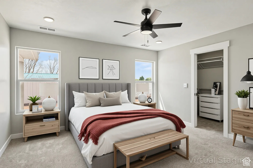 Bedroom with light carpet, a walk in closet, a ceiling fan, baseboards, and visible vents