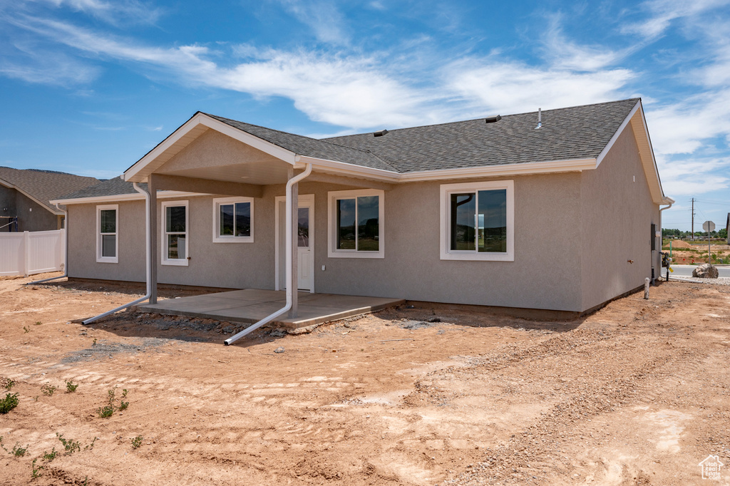 Back of property featuring fence, a patio, stucco siding, and roof with shingles