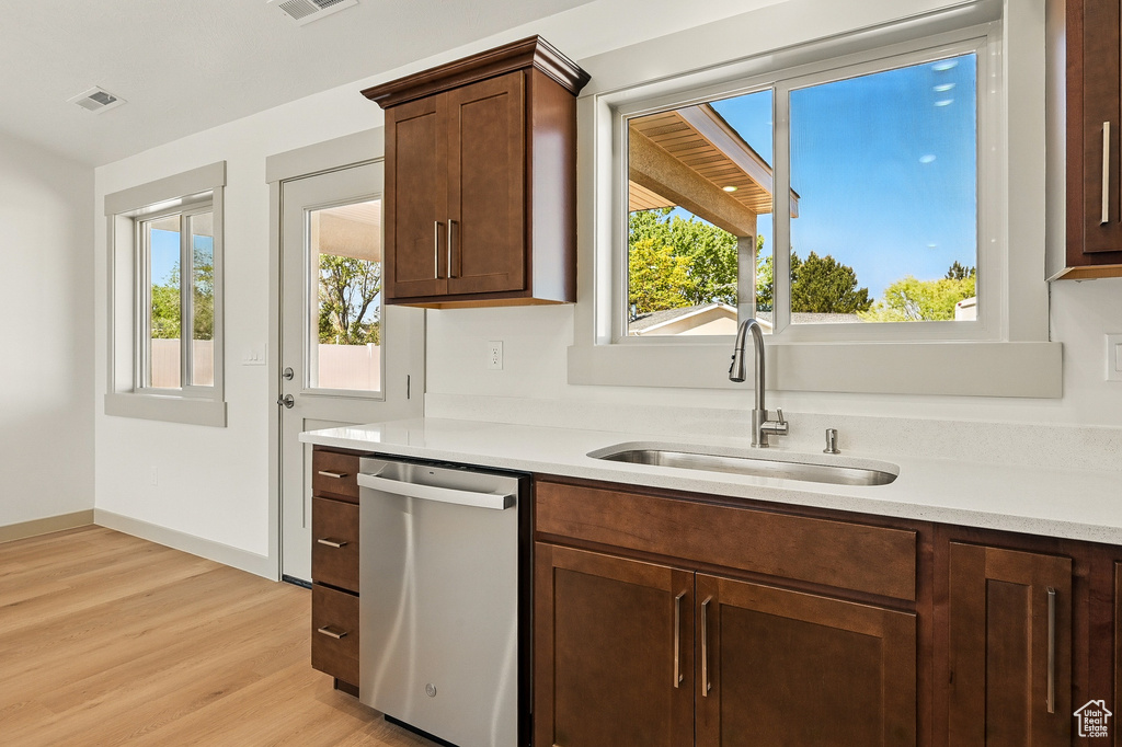 Kitchen with dishwasher, a sink, plenty of natural light, and light wood finished floors